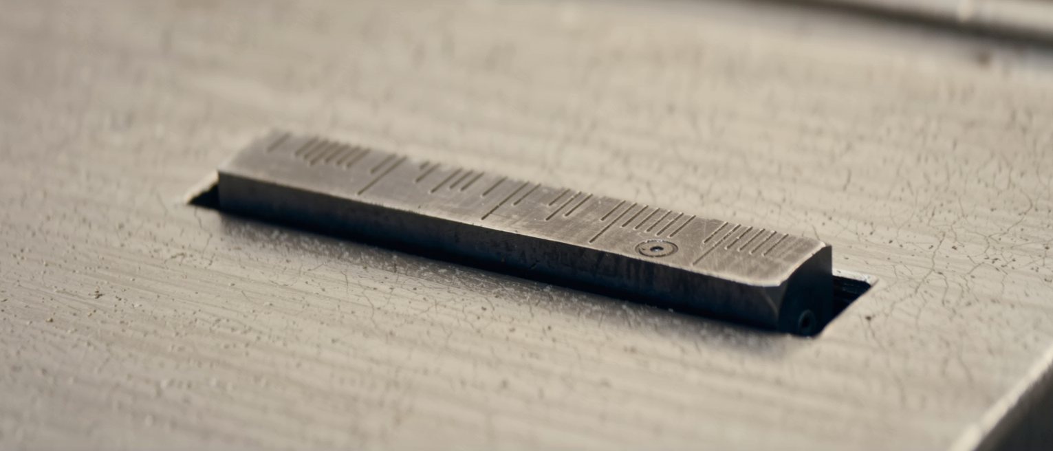 a machined steel gauge block seated exactly inside a cut slot, no daylight at either end