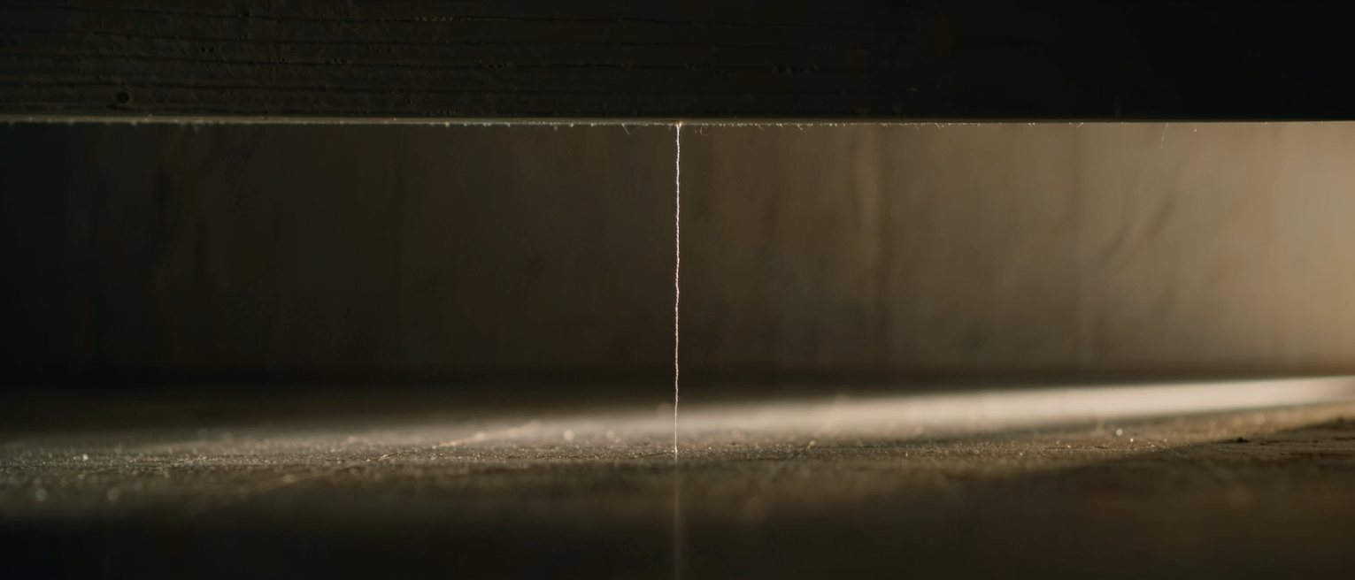 a single fine thread hung from a beam, hanging dead straight and still