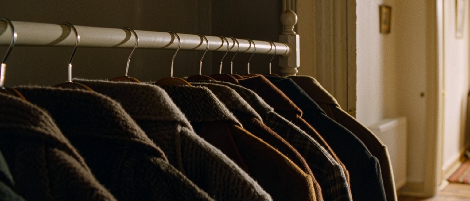 a wardrobe rail at home hung with near-identical coats, all one size, every hanger turned the same way