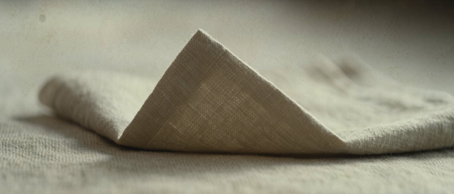 a linen napkin pressed and folded into a square, the crease sharp