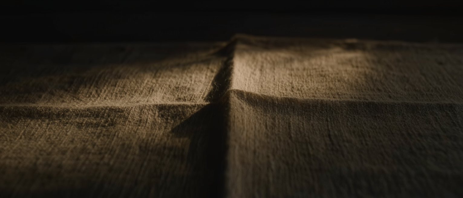 a linen napkin pressed and folded into a square, the crease sharp