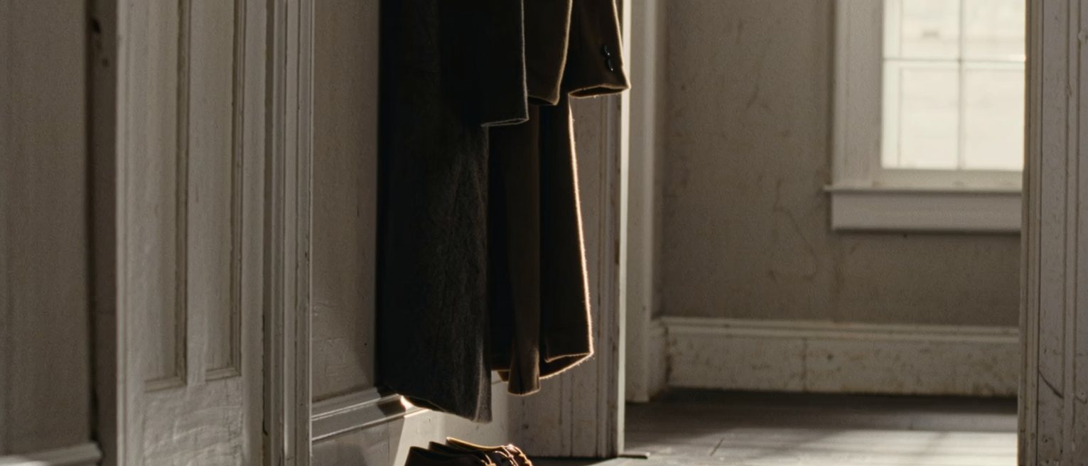 a hall with a coat hung with care on a hook and a pair of shoes lined up beneath it, the visit over, the room left as it was found