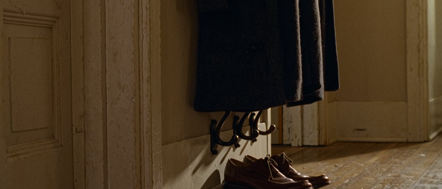 a hall with a coat hung with care on a hook and a pair of shoes lined up beneath it, the visit over, the room left as it was found