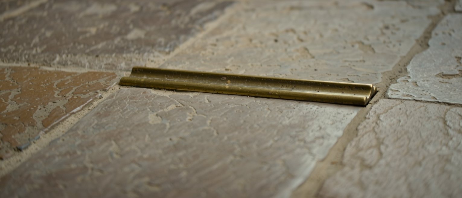 a brass threshold strip let into a stone doorstep, its middle polished bright by years of being crossed