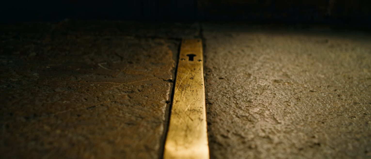 a brass threshold strip let into a stone doorstep, its middle polished bright by years of being crossed