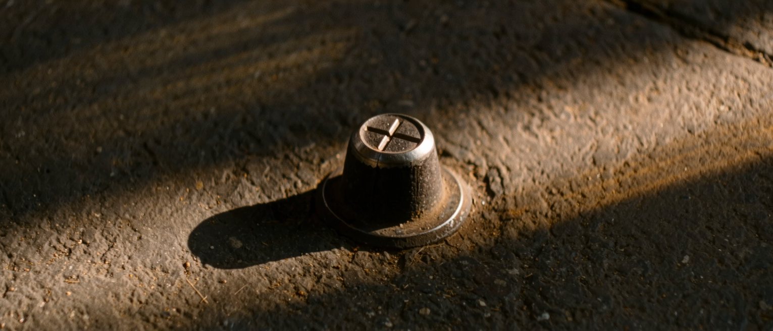 a cast-iron survey marker set flush into a pavement, a cross cut deep into its top