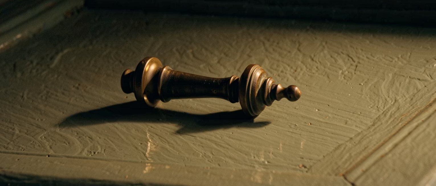 a brass door knocker on a painted door, the knocker lying at rest
