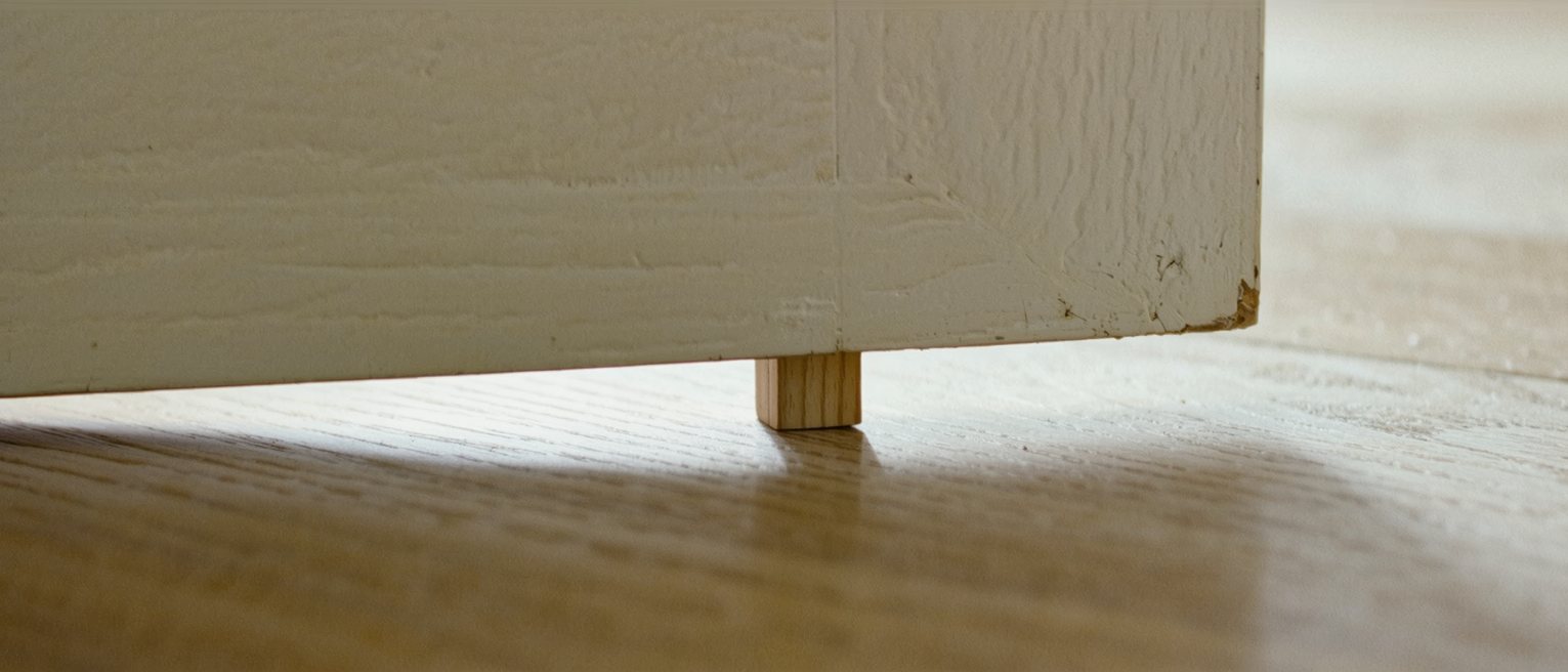 a plain wooden door wedge driven in under the edge of a door, holding it