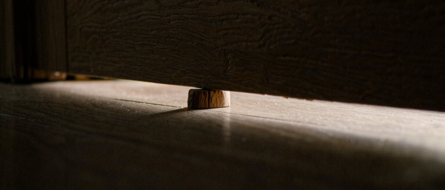 a plain wooden door wedge driven in under the edge of a door, holding it