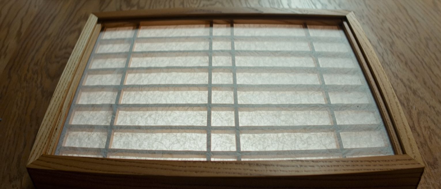 a wooden shoji frame with fresh paper stretched over it, the lattice showing faintly from behind