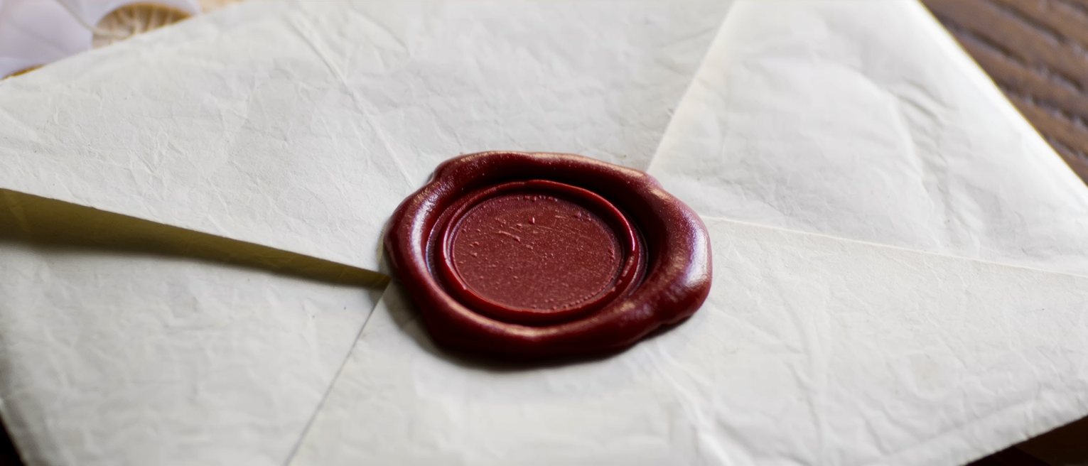 a plain disc of red wax pressed unbroken across the flap of a folded paper packet, the wax smooth and unstamped