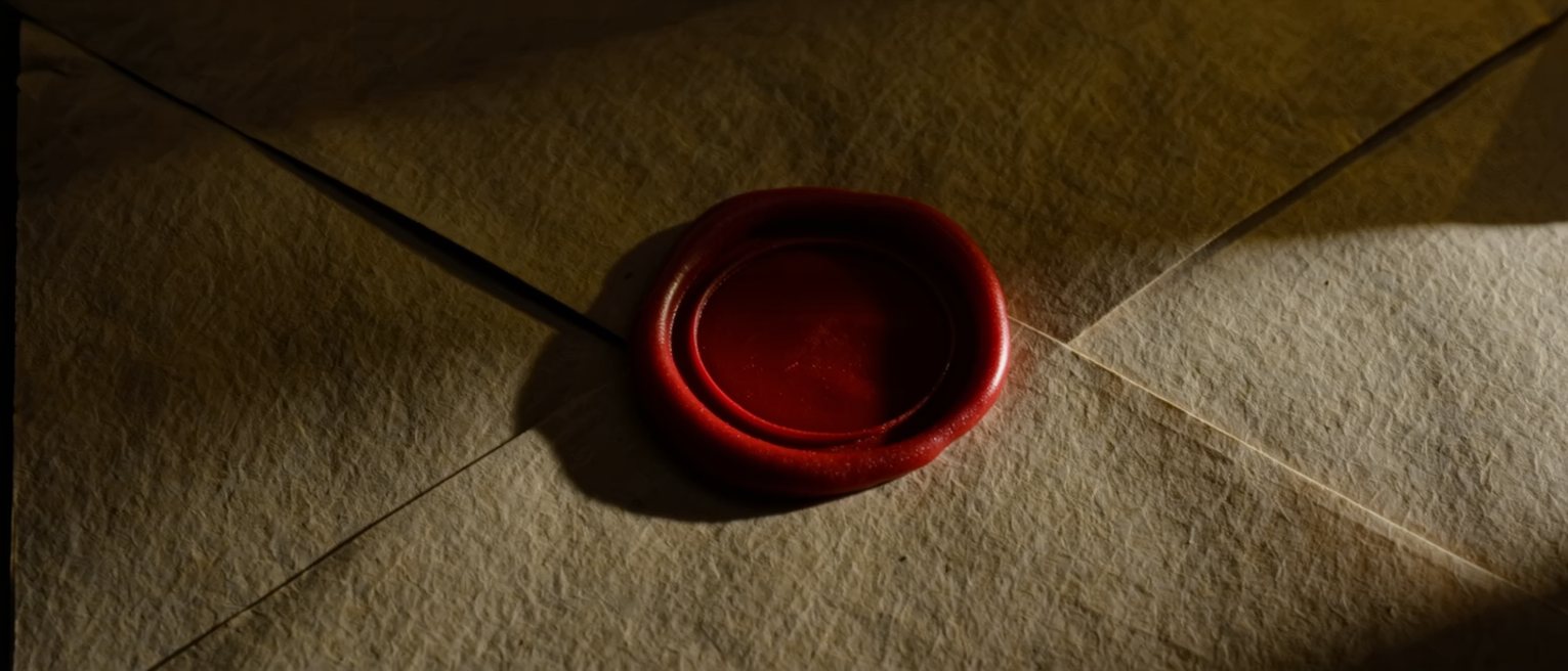 a plain disc of red wax pressed unbroken across the flap of a folded paper packet, the wax smooth and unstamped