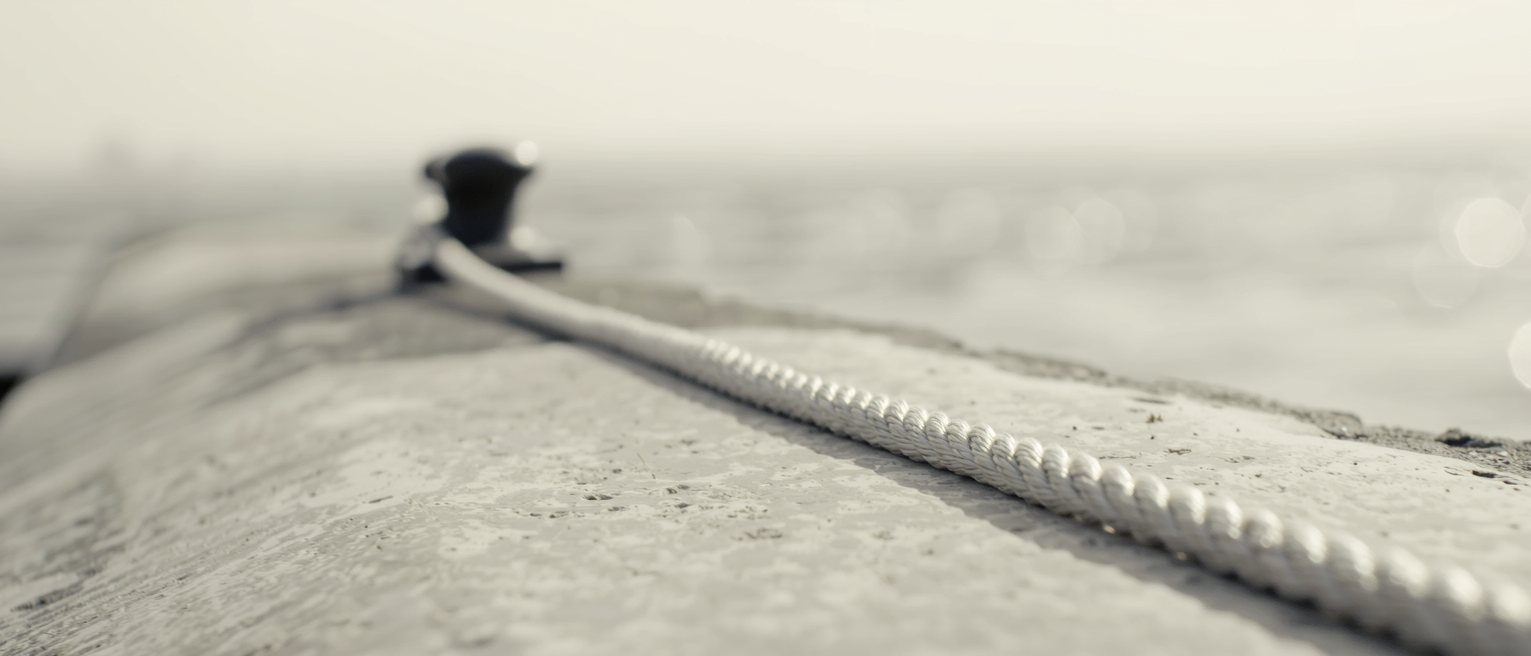 a mooring rope pulled taut from a bollard, running out of frame over water
