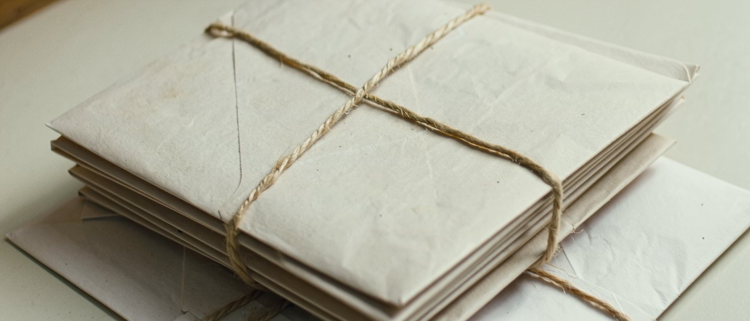 a stack of airmail envelopes bound with string, the edges softened by handling