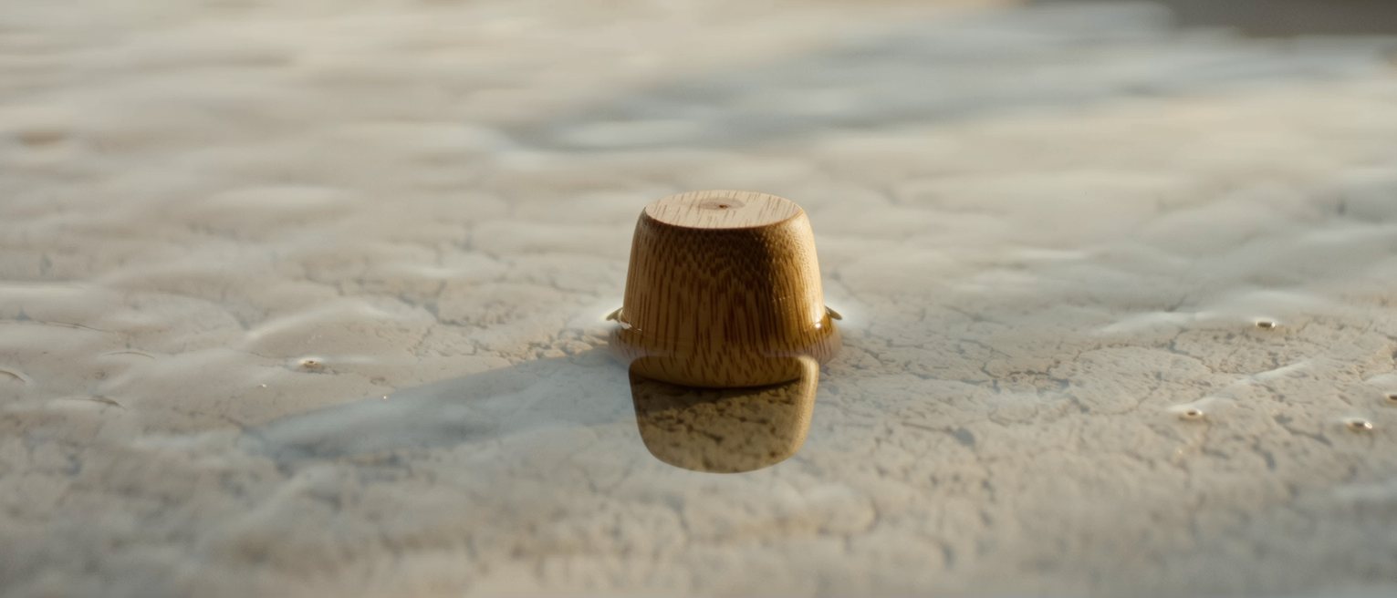 a cypress wood bathing dipper floating upright in still water