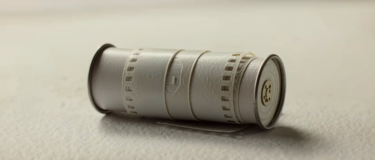 a roll of unexposed film in its metal canister, the leader still tucked in