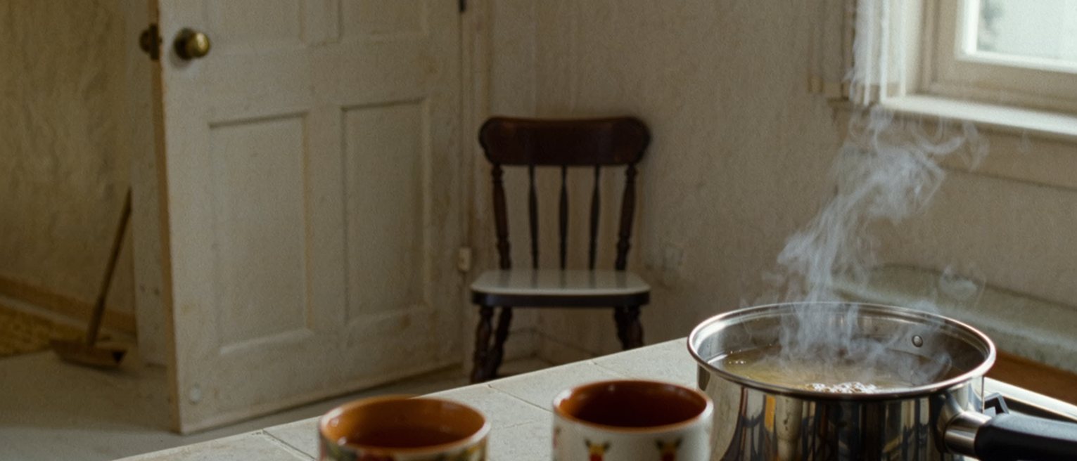 a kitchen with two cups set out and a pot of tea brewing, the second chair turned very slightly toward the door