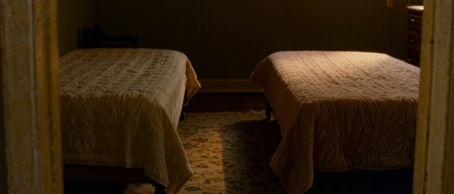 a bedroom with the double bed pushed apart into two singles and a rug laid in the gap between them