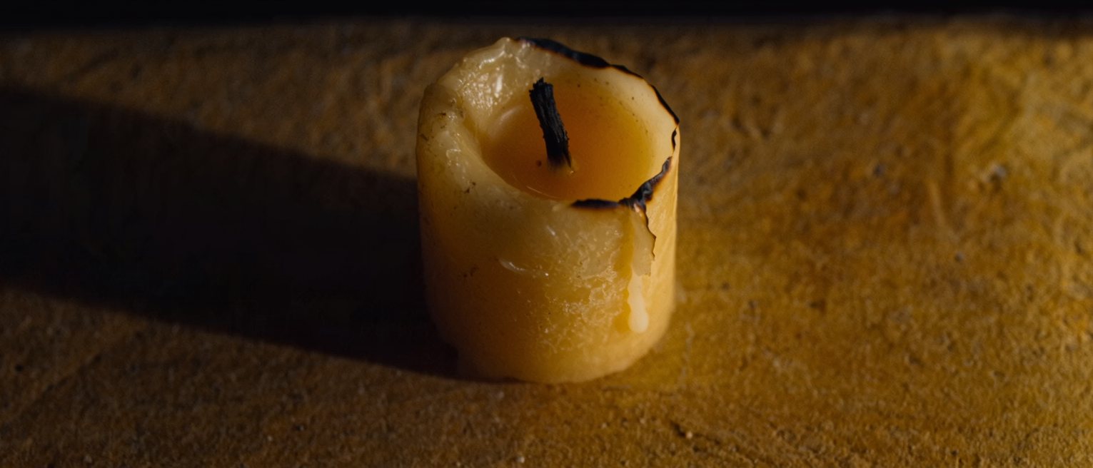 a beeswax candle burned down unevenly on one side, the wax cooled mid-run