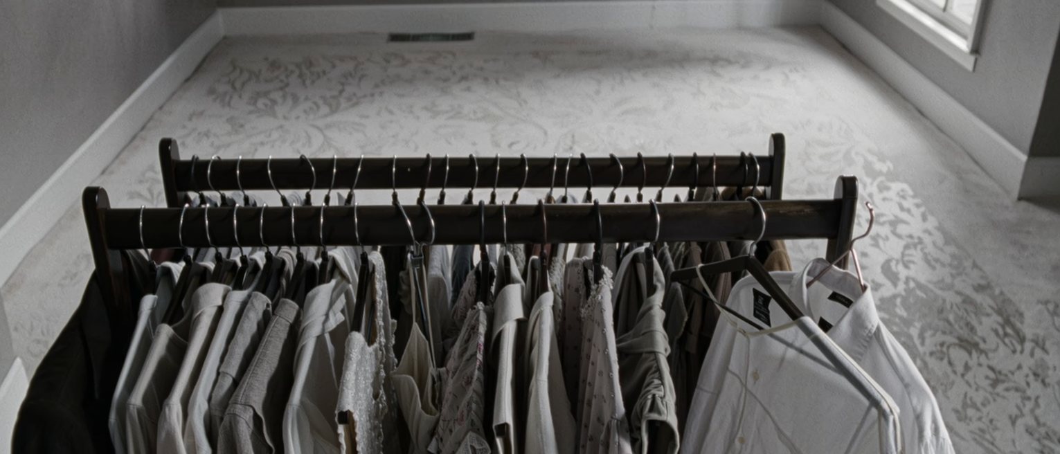 a wardrobe with every dress hung facing the same way and a single plain shirt at the far end, the labels all turned out