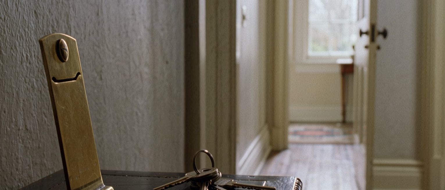 a hall table with a name card gone from its brass holder, the holder still standing, and a set of keys beside it