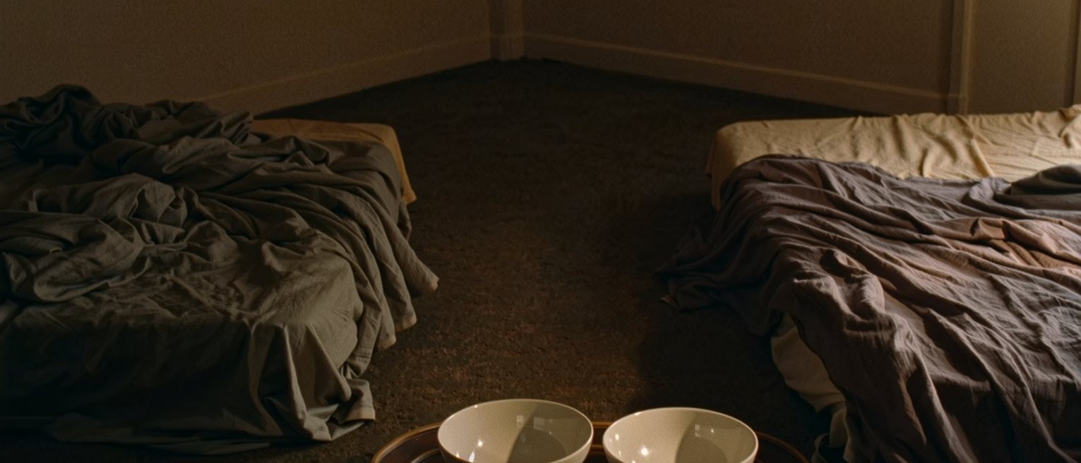 a bedroom with the covers thrown back on both sides and a tray with two empty bowls on the floor, nothing tidied