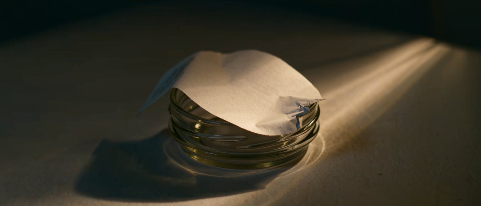 a blank unprinted gummed label half lifted from a glass jar, the adhesive giving way