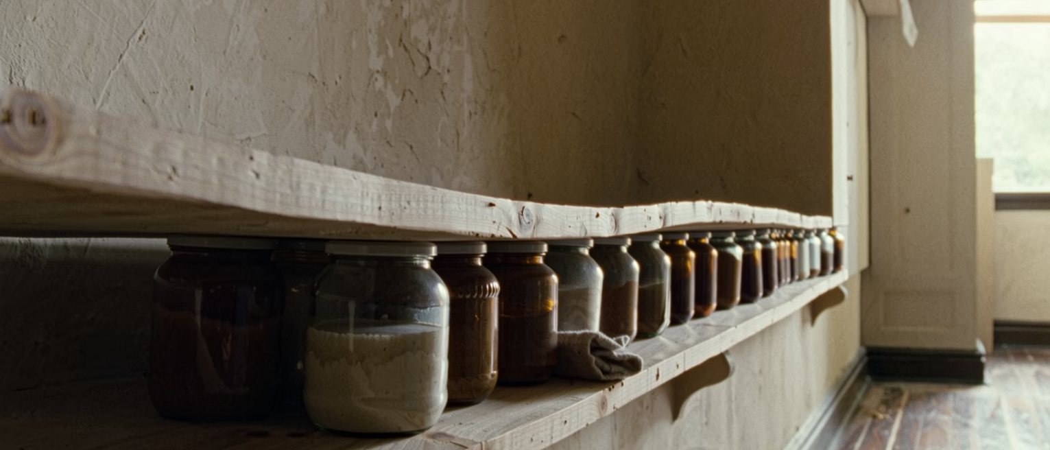 a shelf seen close with a single plank bowed under a row of heavy jars and a folded cloth wedged beneath one end of it