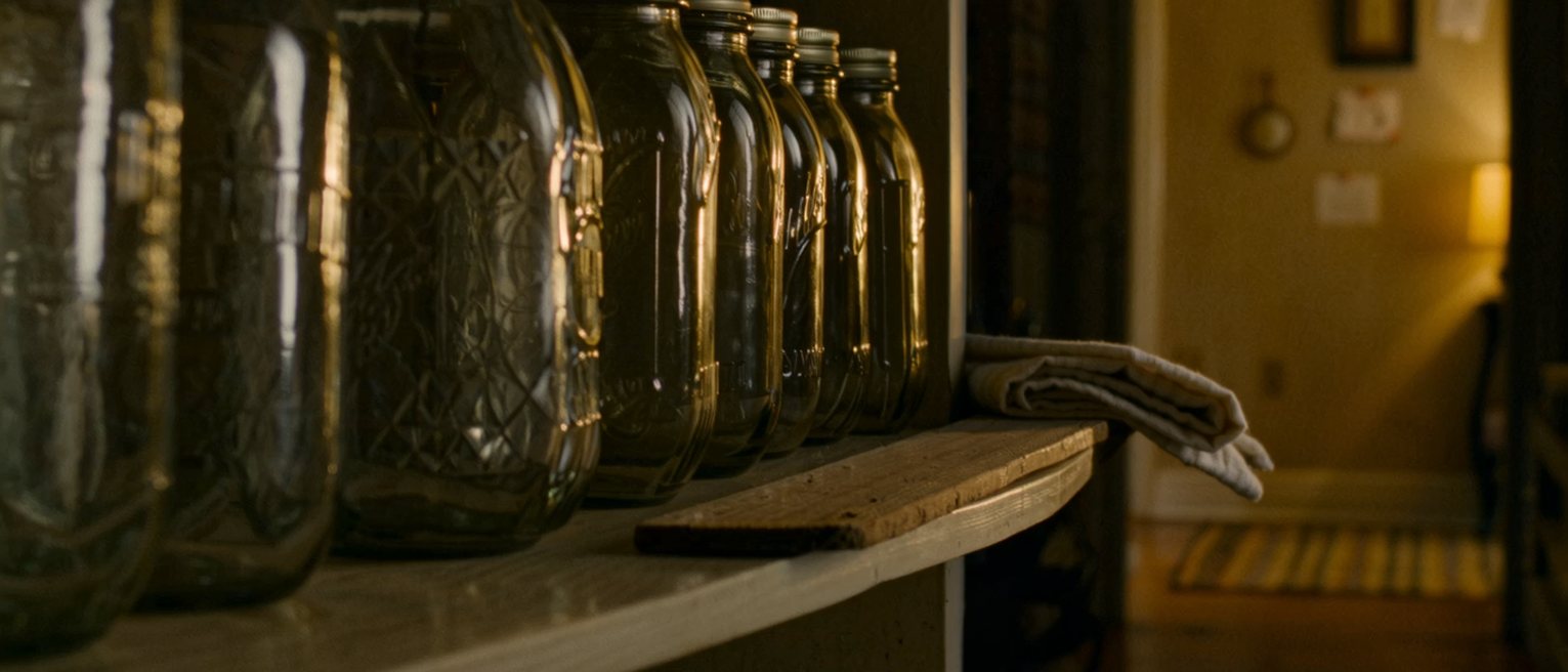 a shelf seen close with a single plank bowed under a row of heavy jars and a folded cloth wedged beneath one end of it