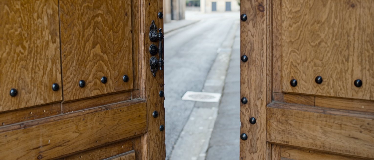 a studded wooden door standing open onto a lit street