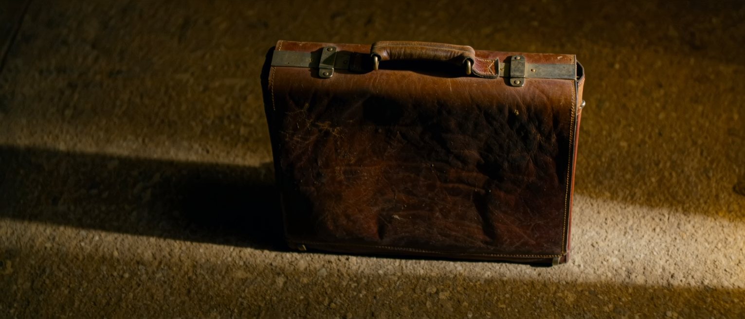 a worn leather briefcase standing closed on its clasps