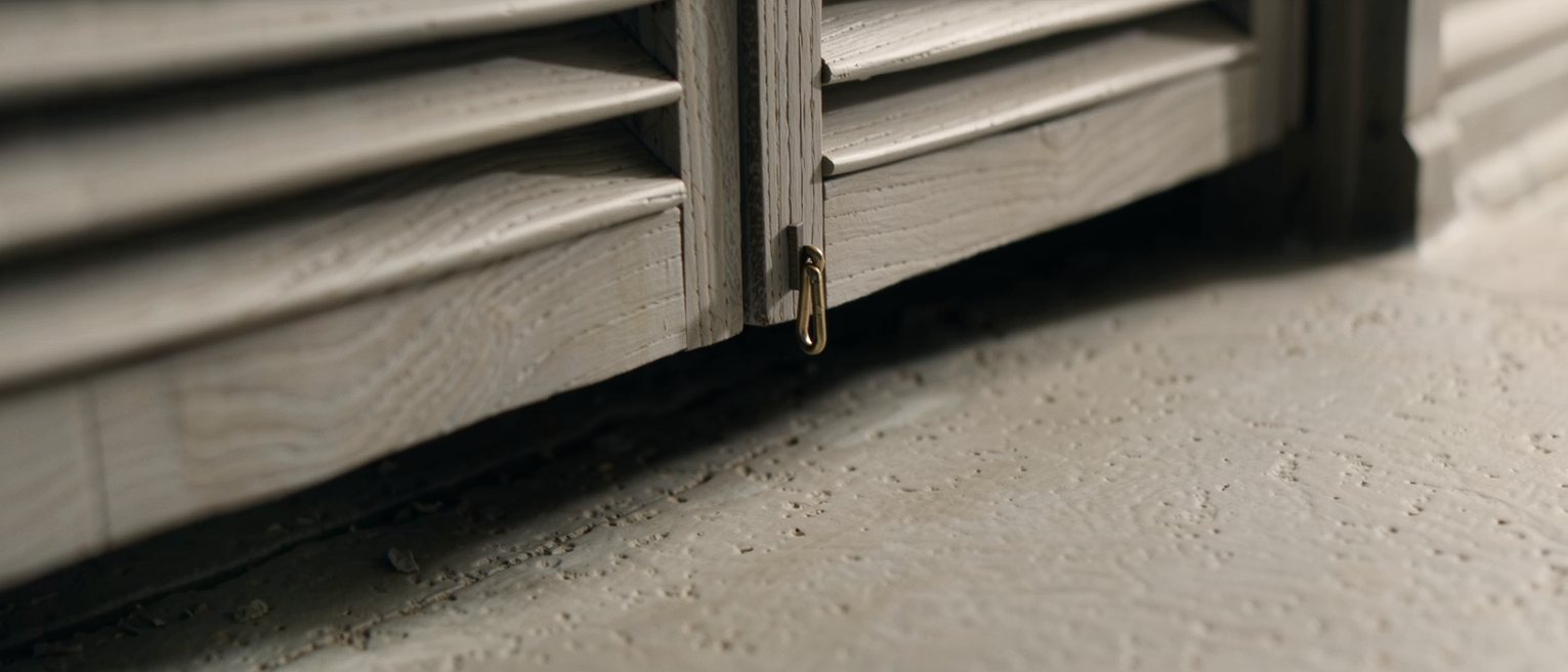 a hinged wooden shutter closed across a shop front, its hasp dropped
