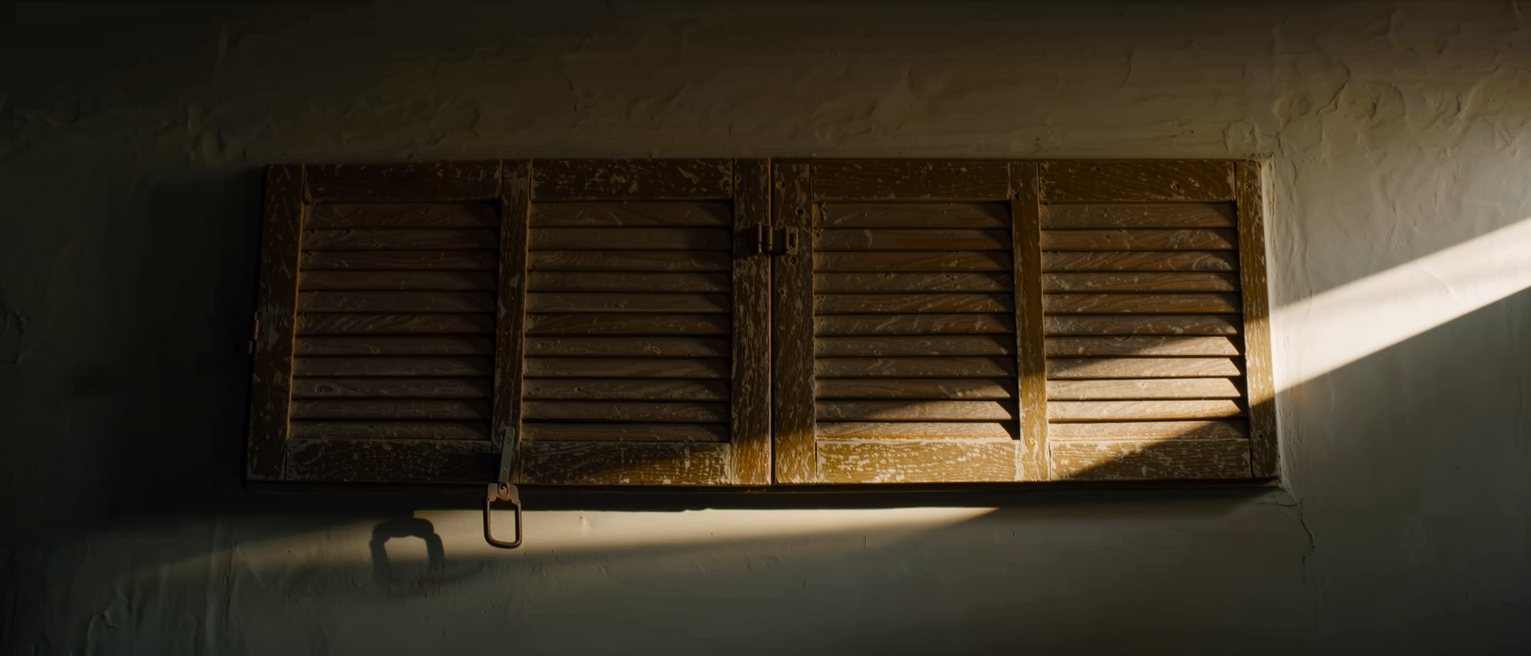 a hinged wooden shutter closed across a shop front, its hasp dropped