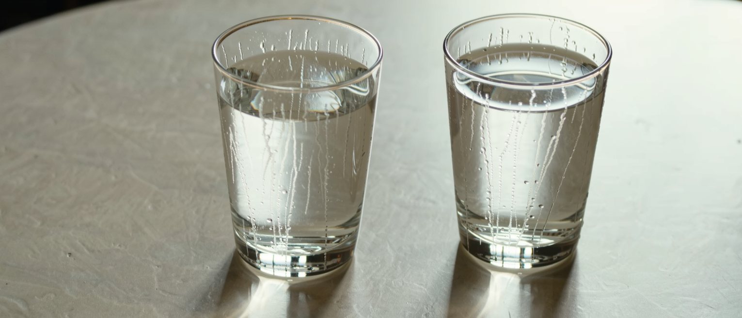 two glasses of cold water set down on a café table, the condensation already running