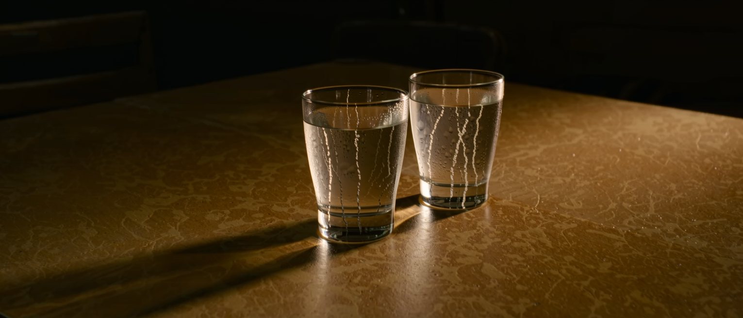 two glasses of cold water set down on a café table, the condensation already running