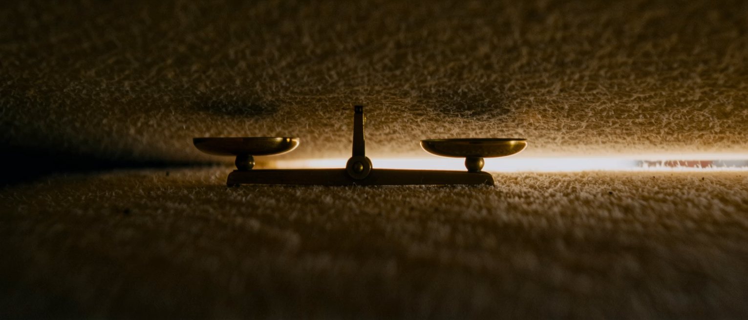 a brass beam balance standing level, one shallow pan hanging at each end of the beam