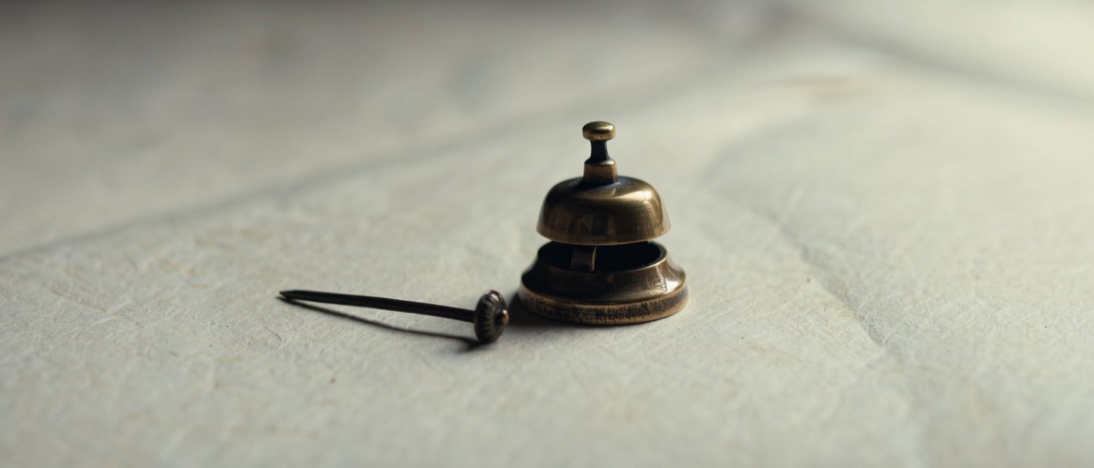 a small bronze bell with its striker laid down beside it, neither touching