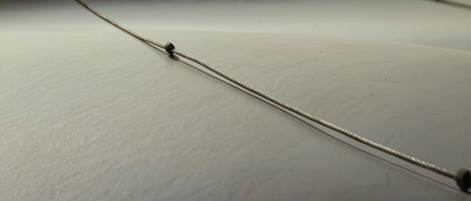 a steel guy wire strained tight between two anchors, no slack anywhere along its length