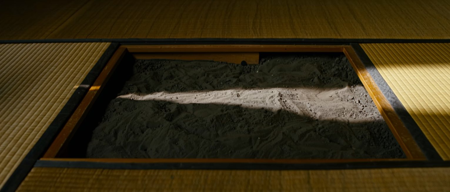 a sunken hearth cut square into tatami matting, the ash inside it raked level
