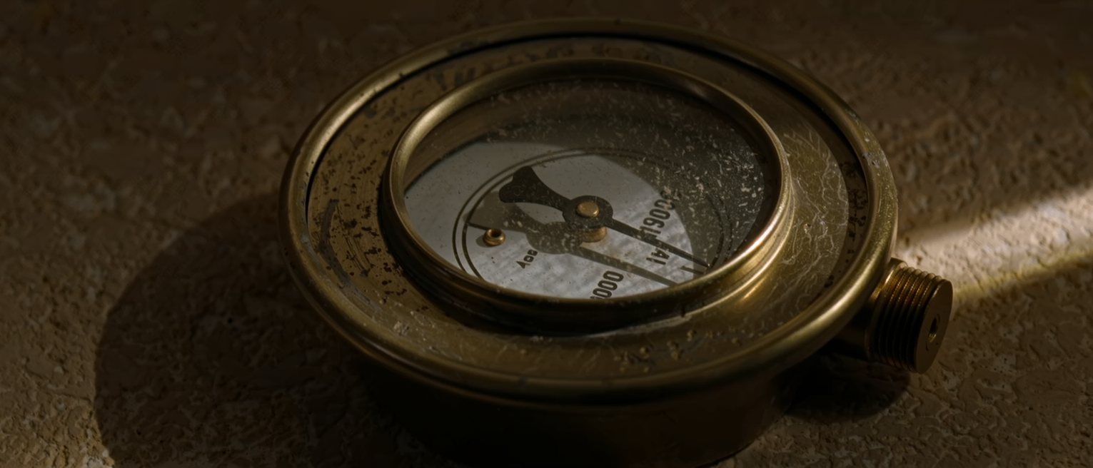 a brass pressure gauge with its needle resting flat at zero, the glass dusty