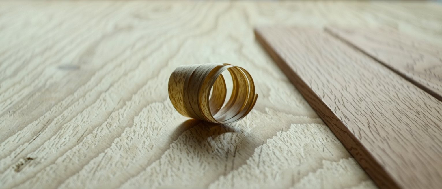a curl of plane shavings on a bench beside the board they came off