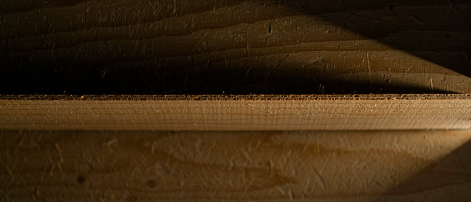 a shelf of pale plywood swept bare, its front edge rubbed bright where hands have passed along it