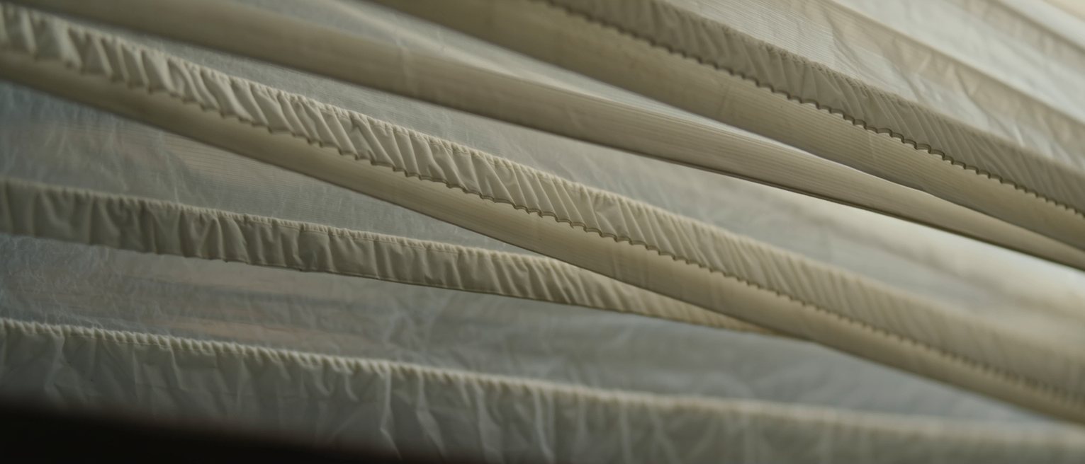 the overlapping strips of a heavy translucent plastic curtain hanging still, each strip creased down its length