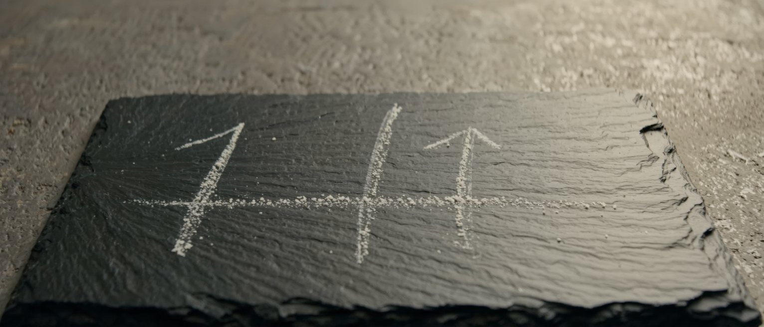 a tally of chalk strokes on dark slate, half of them rubbed away