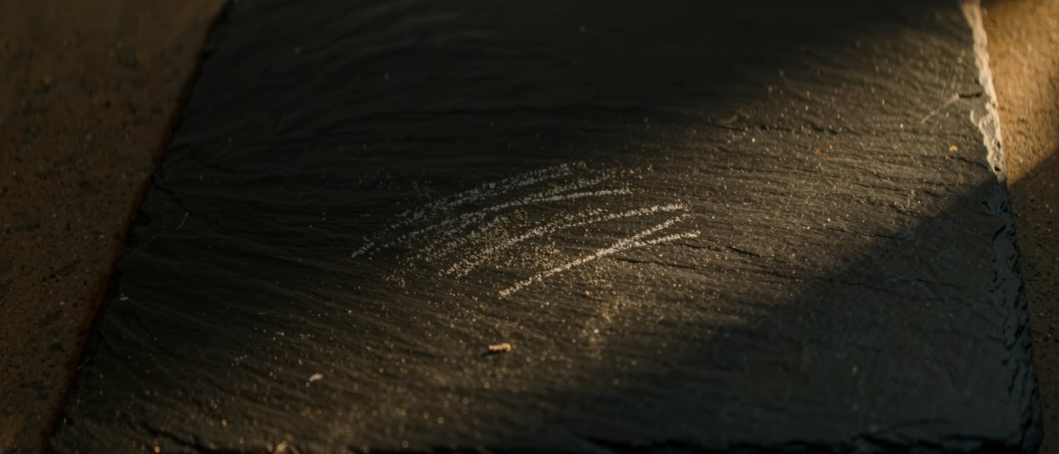 a tally of chalk strokes on dark slate, half of them rubbed away