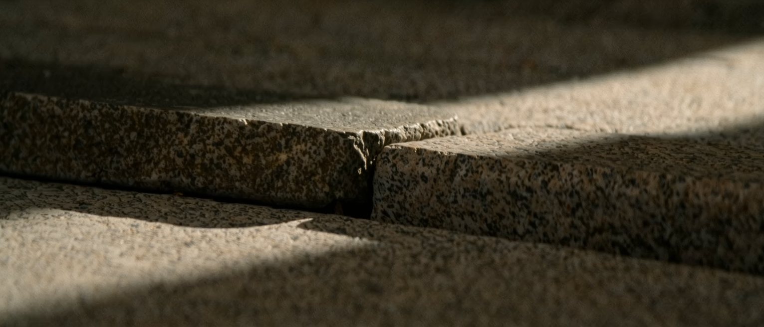 two granite kerbstones meeting along one straight joint, the left block weathered smooth and the right still sharp-arrised