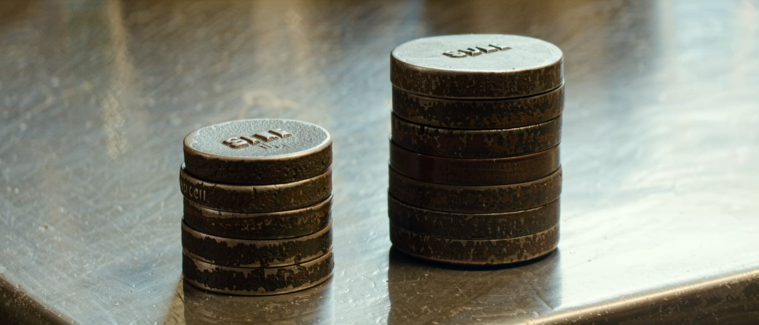 two columns of cast-iron calibration weights stacked on a workbench, one column plainly taller than the other