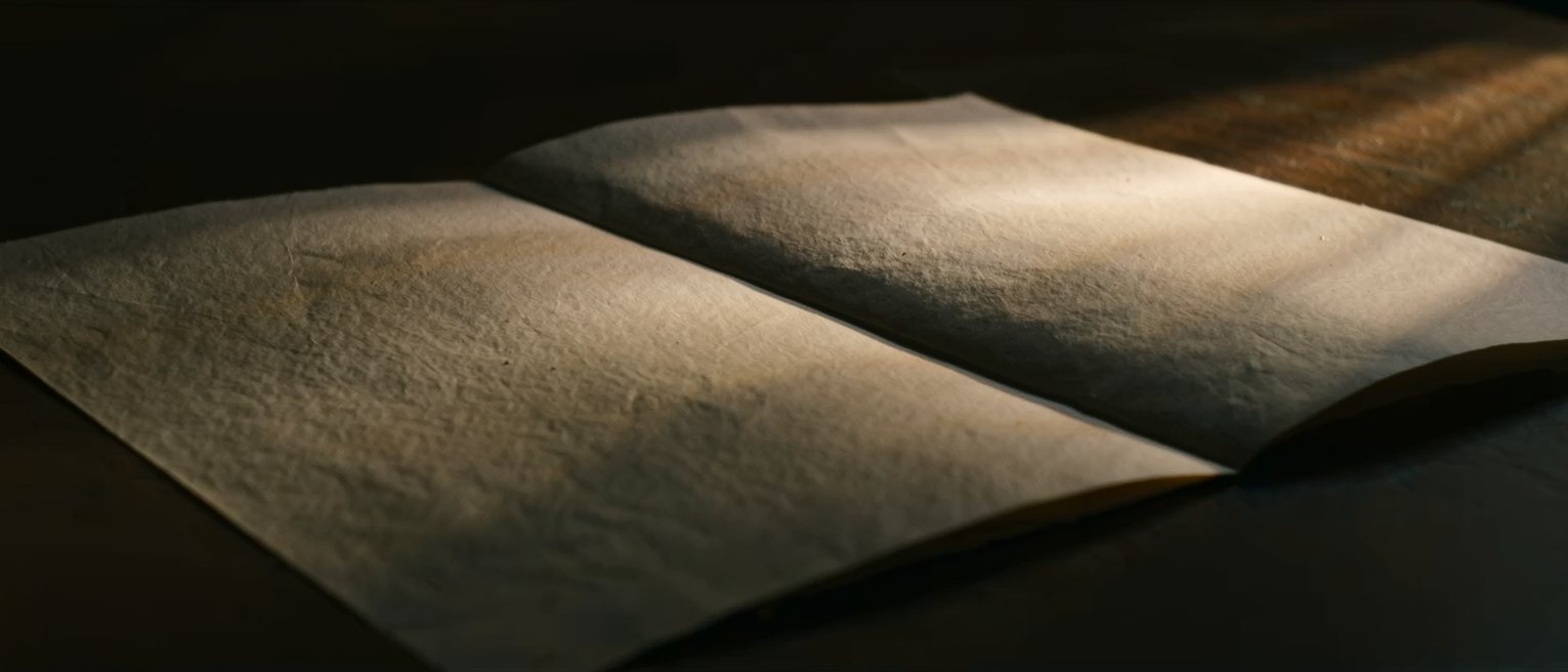 a single sheet of writing paper folded once and left unopened on a table, the fold standing up sharply