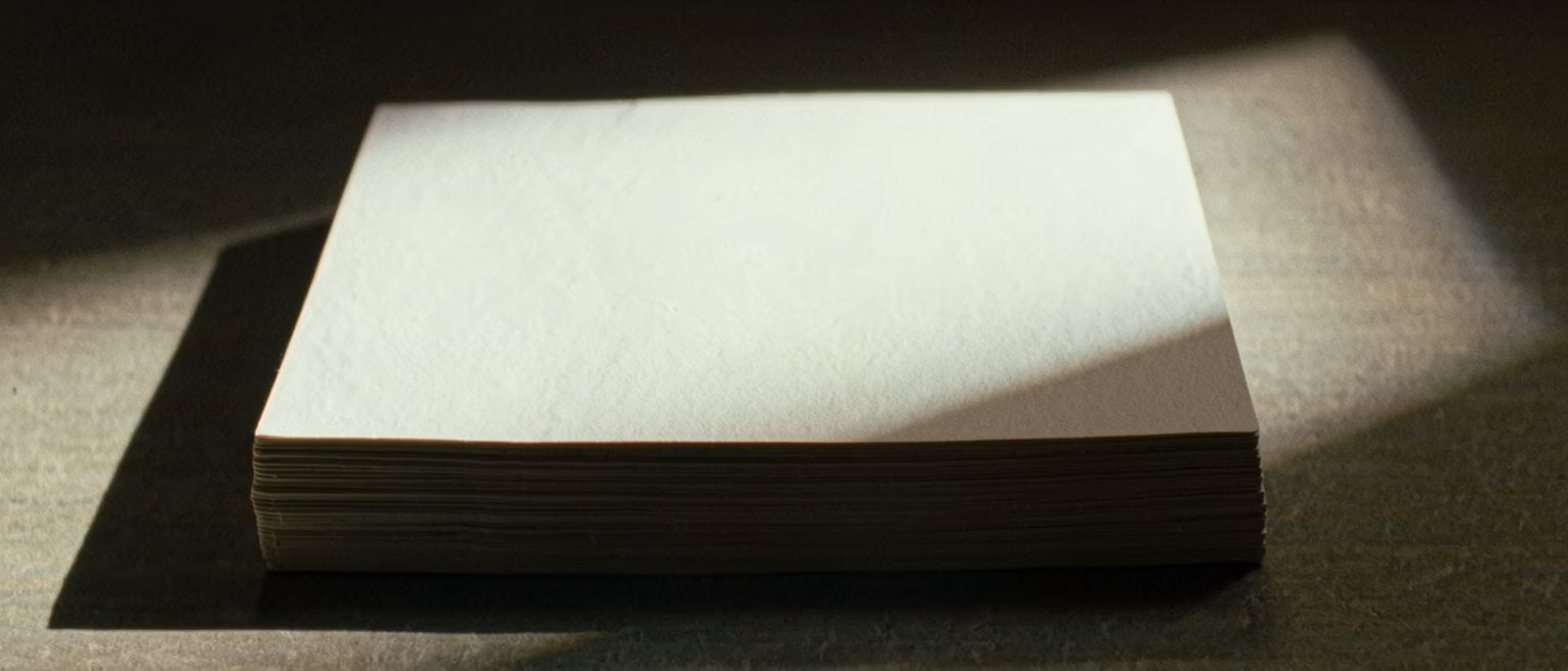 a squared stack of blank white cards on a table, the edges perfectly aligned