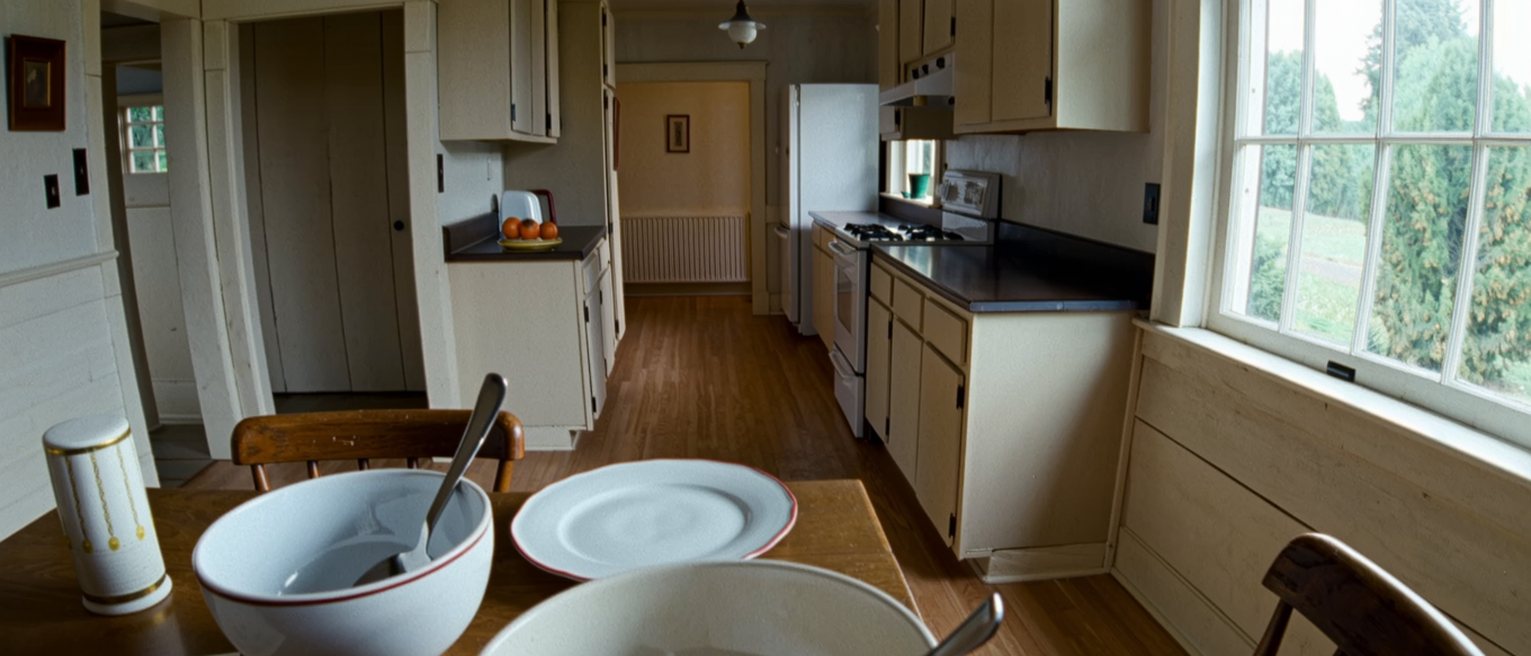 a kitchen on a Tuesday: the same bowl, the same spoon, the same chair, the post on the table, everything known